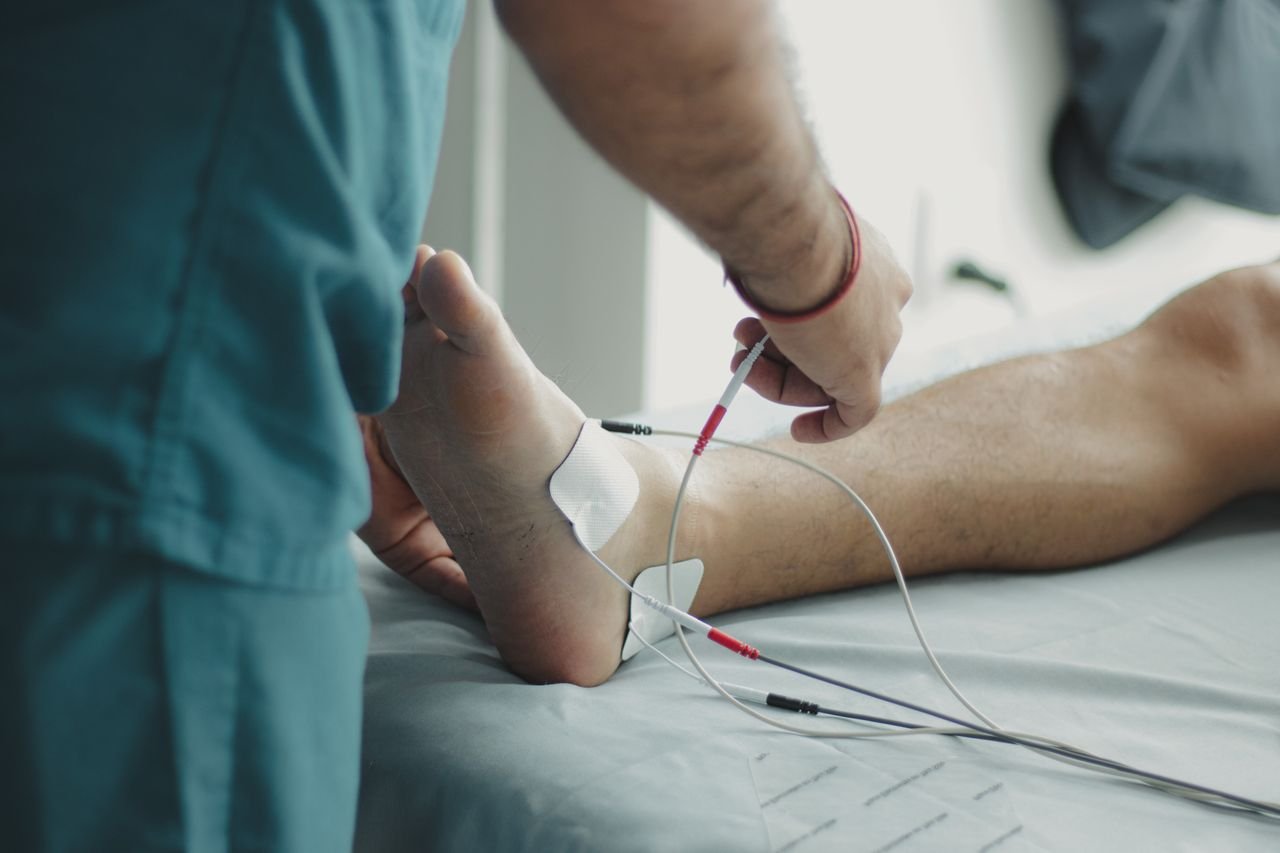 Close-up of a healthcare worker examining a patients foot with medical equipment in a hospital setting.